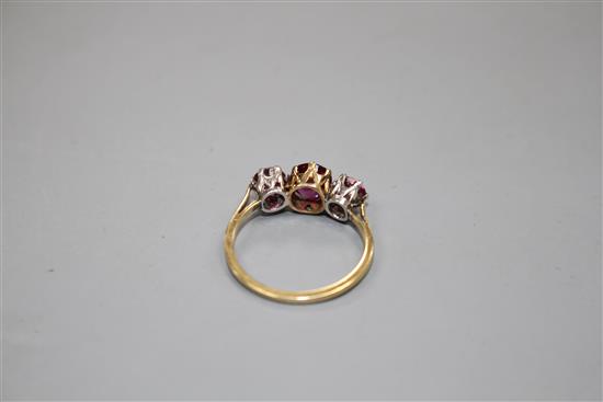 An 18ct and three stone ruby and garnet?? set dress ring, size M, gross 2.7 grams.